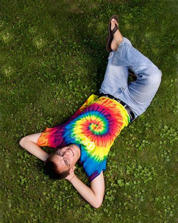 Man laying on grass in a tie-dye shirt